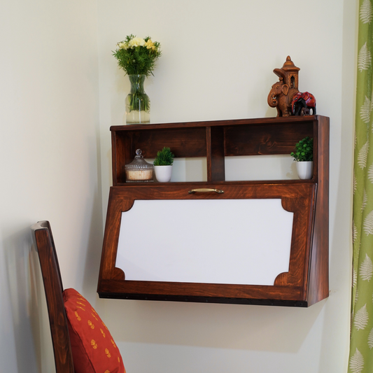 CustHum - Closed view of a wall-mounted desk in dark wood tone with writable white laminate on front panel, two small open top shelves, decorated with small planters and artefacts